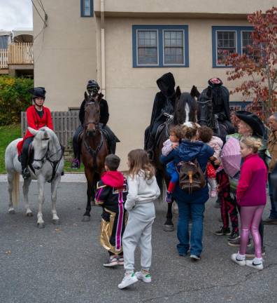 Children gather in front of, from left, Icabod Crane on Bitty, Plague Doctor on Z boy, Day of the Dead on Eagle and the Headless Horseman on Falcon.