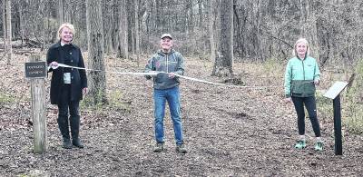 From left, Anne Lopuch, Neil Saurwein and Christine Dunbar hold the ribbon.
