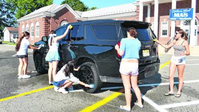 Members of the Sparta girls' tennis team wash a car.