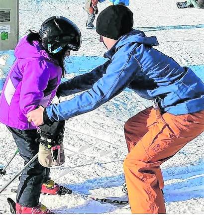 <b>Cory Gorczycki helps a child on the ski slopes.</b>