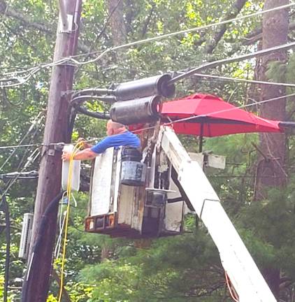 In an attempt to make Saturday's heat more bearable, a utility worker at the end of South Shore Trail in Sparta, brings an umbrella and a box fan up to his work site. (Photo by Shannon Kuratli).