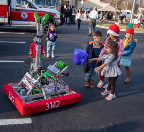 Children play catch with Newton High School’s robot, which was the most popular attraction at the event.