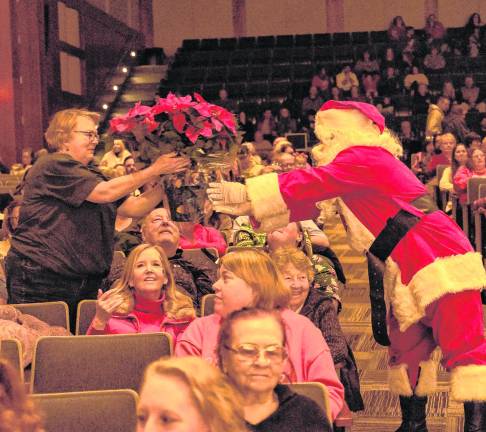 Santa Claus hands flowers to a member of the audience.