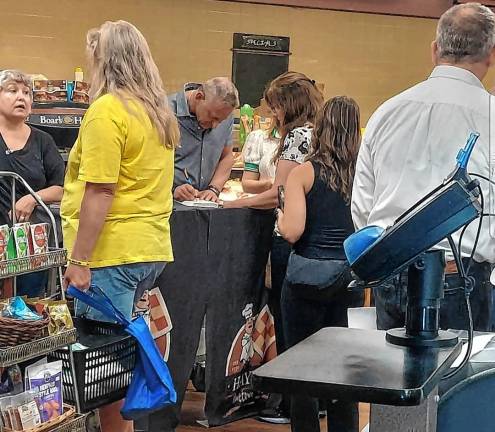 Clark Fredericks signs his book, ‘Scarred: A Memoir of a Childhood Stolen and a Life Redeemed,’ on Wednesday, July 29 in Newton.
