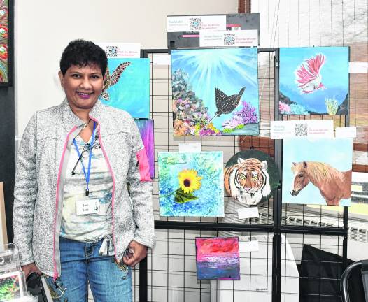 Sue Siva is shown in front of her artwork.