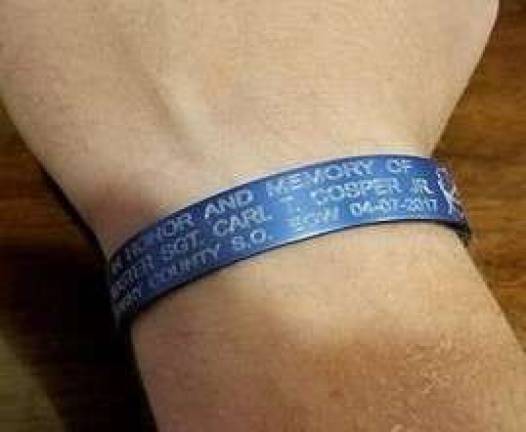 Andover Township Police Department Ptl. Alex Price displays a bracelet engraved with the name and information of Master Sgt. Carl T. Cooper, Jr., a Missouri police officer lost in the line of duty last year. Officer Price will be riding to honor his memory in the 2018 Police Unity Tour, beginning Wednesday, May 9. Photo by Mandy Coriston