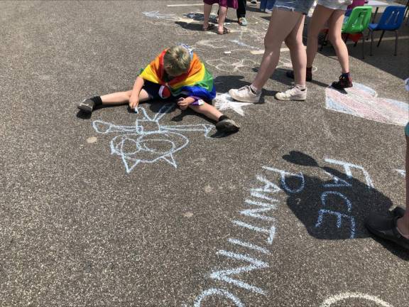A boy uses chalk to draw on the pavement.