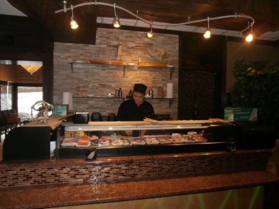 A sushi chef, hailing from Japan, freshly prepares rolls.