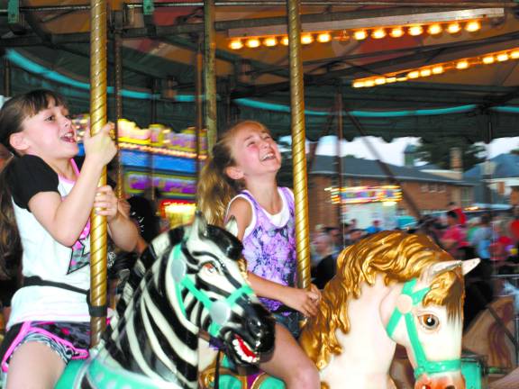 Photos by John Church Melanie Gilmore, 8, and Ashley Gilmore, 8, on the merry-go-round Friday night.