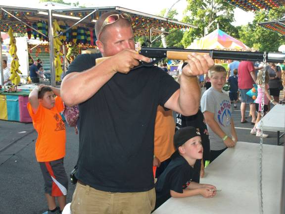 Justin Vozza takes aim with a pop gun as his nephew Kristian Vozza, 6, watches.