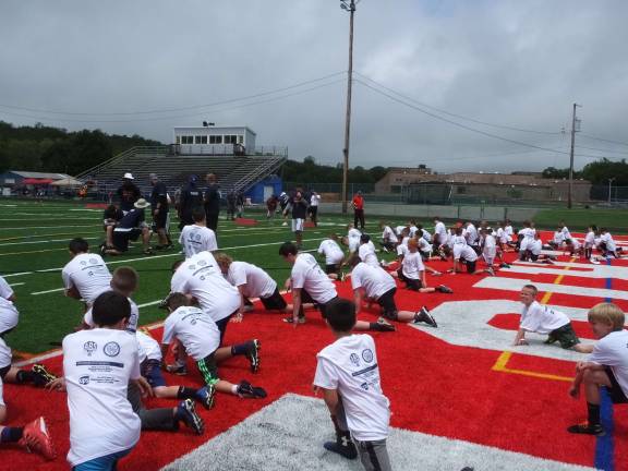 Youth football players loosen up on the turf.