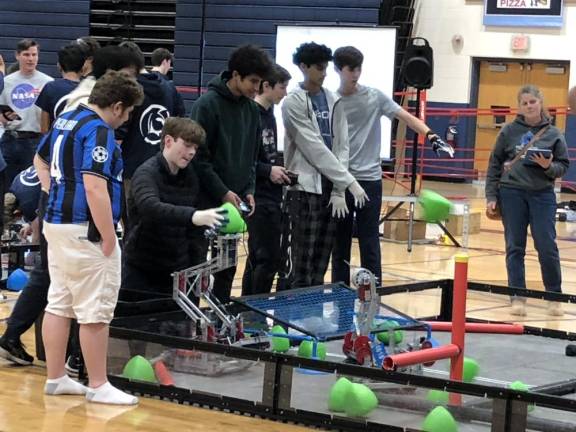 A student places an acorn-shaped tri-ball on the team’s robot. During a match, the teams try to get the most tri-balls in the netted zone. (Photos by Kathy Shwiff)
