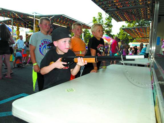 Kristian Vozza, 6, of Sparta, takes aim with a pop gun that is almost as big as he is at the Our Lady of the Lake carnival Friday night.