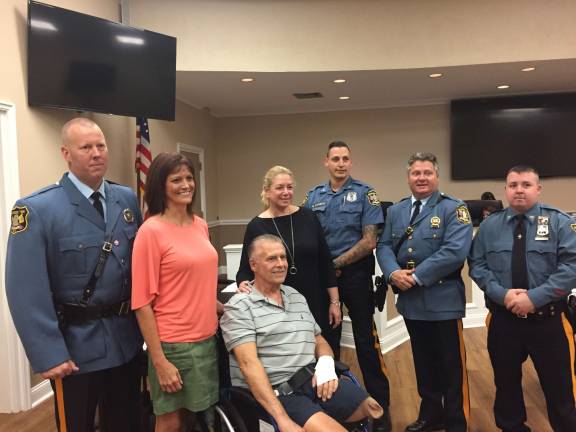 Tom Heller, center, is flanked on the left by his wife, Laura Heller, and on the right by Monica Transier, and by officers of the Jefferson Township Police Department.