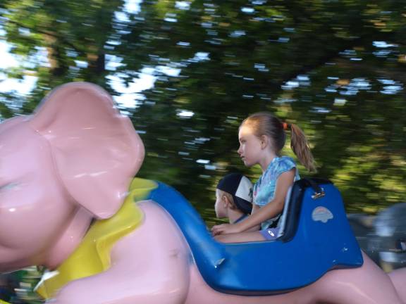 Jimmy, 3, and Kayla, 7, of Andover Township, go for a spin on a pink elephant.