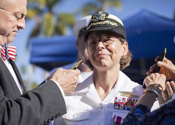 U.S. Navy photo by Mass Communication Specialist 3rd Class Gregory A. Harden II/Released Rear Adm. Linnea J. Sommer-Weddington receives her rear admiral shoulder boards from her husband, Andy Weddington, at her promotion ceremony. Sommer-Weddington is the first female reserve officer to carry one star on her shoulder boards within the Information Dominance Warfare community.