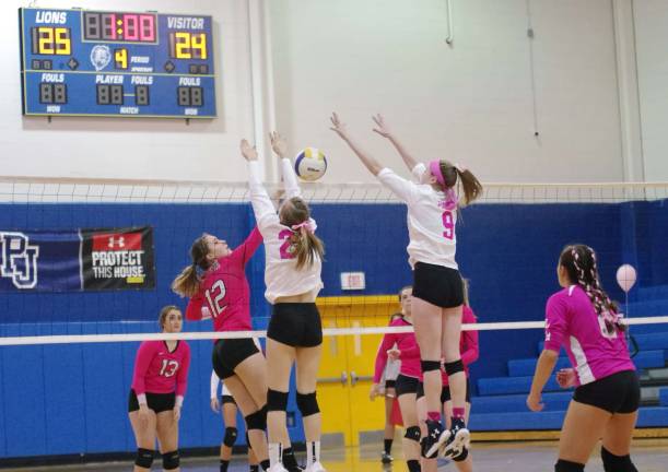 Jefferson's Audrey Oostdyk (12) gets a hand on the ball as Pope John defenders react by leaping above the net in the final match. Oostdyk accomplished one service point, four kills and one dig.