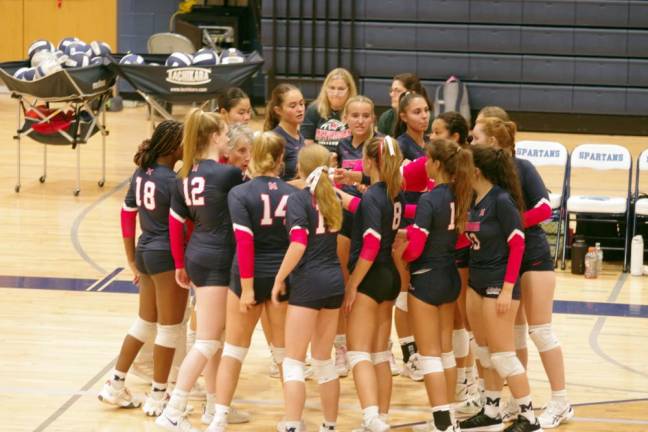 The Mendham varsity volleyball team and staff in a huddle during a break.