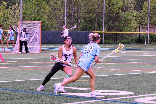 A Spartan carries the ball with her crosse as a Passaic Valley Hornet keeps pace.
