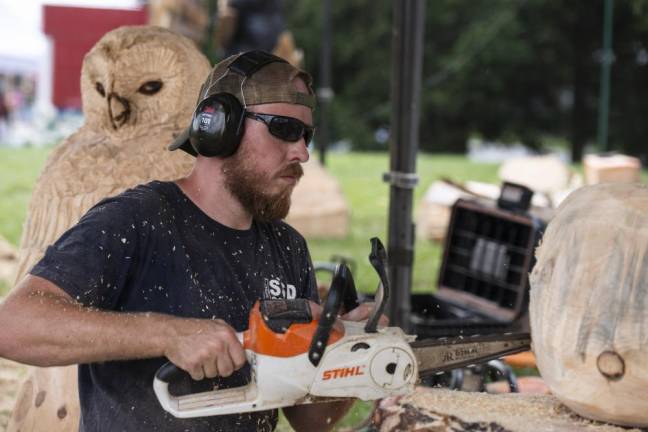 FR26 Chris Nielsen of Byram creates a sculpture with a chainsaw at the tent of Freehand Custom Carvings. (Photo by John Hester)