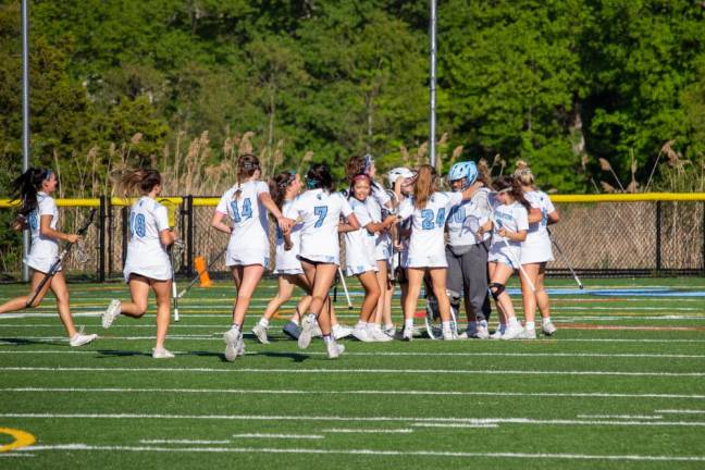 Spartan teammates rush to hug their goaltender Sama Elhamouly (00) after their win against Vernon during the first round of the girls varsity lacrosse state tournament Thursday, May 25 in Sparta.