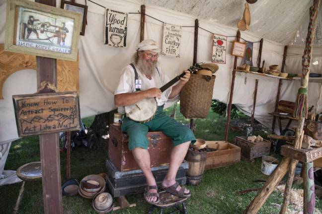 FR25 Roger Abrahamson, a bowl turner and wood worker, plays banjo in his shop tent at the New Jersey State Fair. (Photo by John Hester)