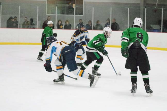 A Kinnelon player maneuvers the puck between two Sparta-Jefferson United skaters.