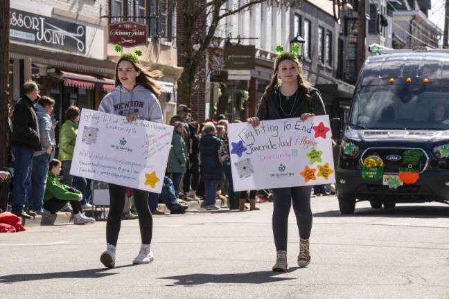 Two volunteers from the Weekend Bag program, which fights hunger, march in the parade.