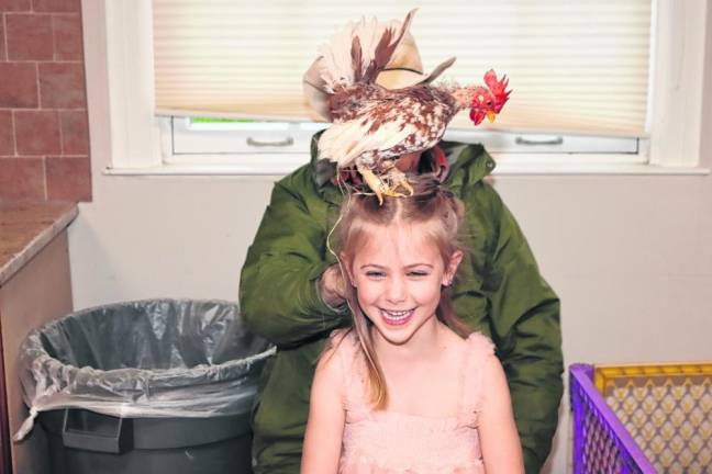 A chicken sits on the head of Camille Sherman, 5.