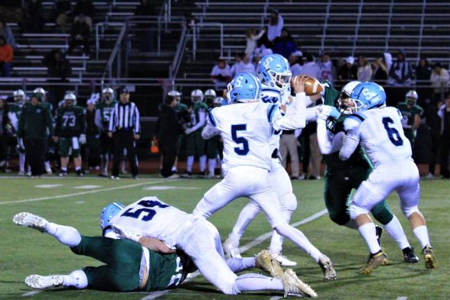 Quarterback Kenny Oelkers passes the ball to a waiting Spartan as the Raiders around him are blocked.
