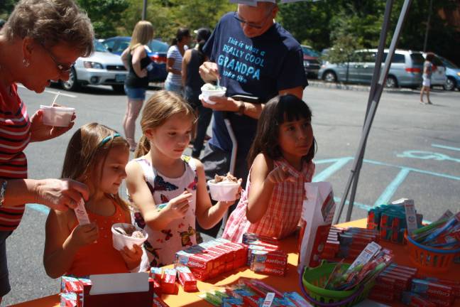 Caitlin Steinwand, 5, Cera Steinwand, 7, and Kaitlin Lawrence stock up on complimentary toothbrushes and toothpaste. Grandmother Dianne Neveras helps out.