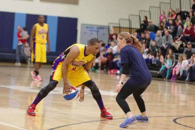 Harlem Wizard Devon "Livewire" Curry does some fancy dribbling while shadowed by an opponent.