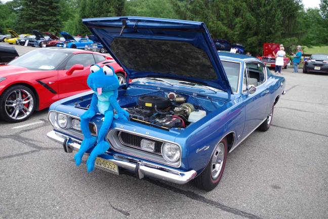 A strange looking blue creature sitting on a blue 1967 Plymouth Barracuda.