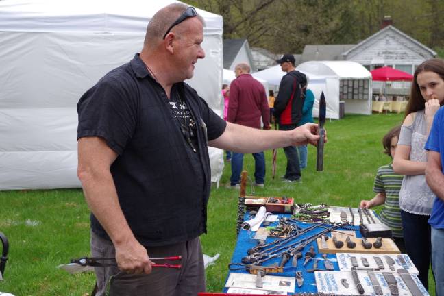Artist and metal worker William Barrett shows off a knife he made out of Damascus steel at his table of creations.