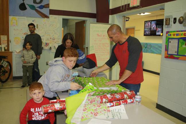 The Denicola family volunteers their time to wrap some gifts Friday night at Helen Morgan school.