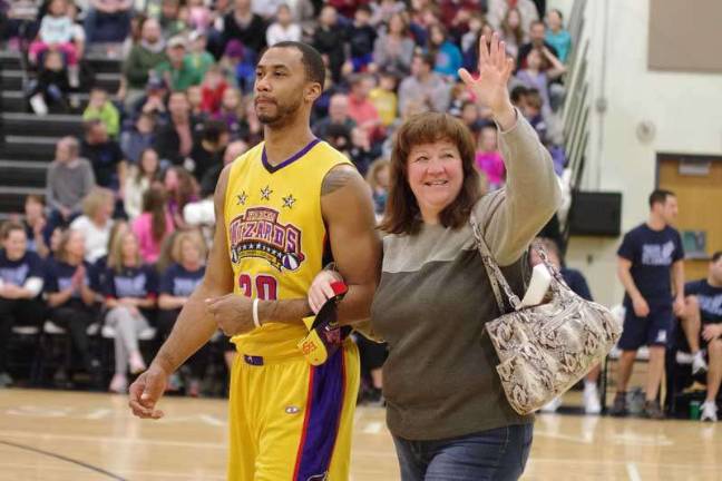 Harlem Wizard Timothy "Tomahawk" Stukes escorts Sparta resident Tracey Puleo back to her seat after helping retrieve her pocketbook swiped by one of his teammates.