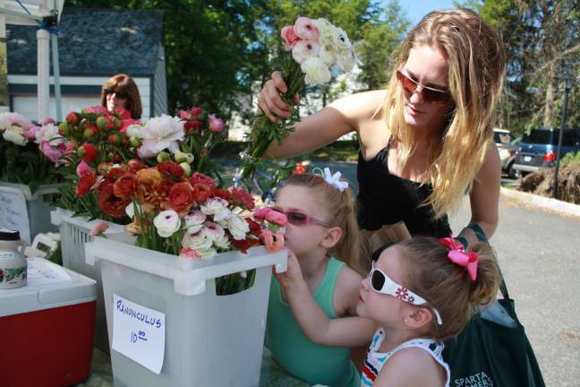 Adriana Hoppe, 6, checks out the flowers at the Sparta Farmer's Market with her mom Amanda and sister Mieka, 3.