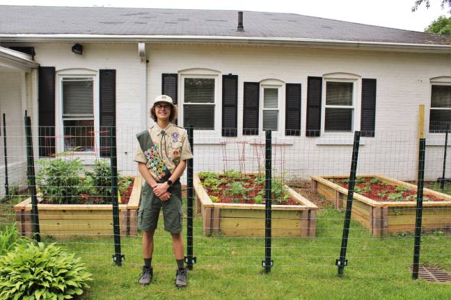 Eagle Scout Gerisch stands before his project of three raised food gardens