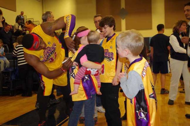 Harlem Wizard Leon "Space Jam" Sewell autographs a young fans jersey.