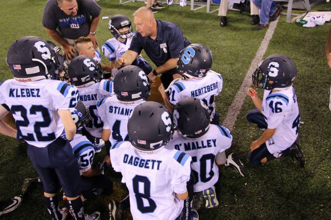 Sparta Spartans 3rd graders huddling around coach, and Sparta mayor, Josh Hertzberg after the team scored and came off the field.