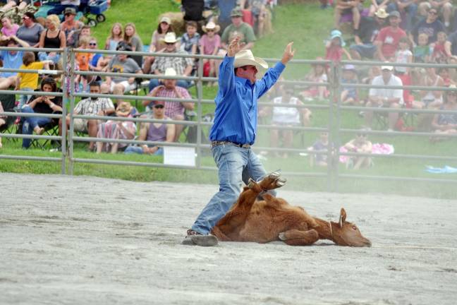 Rodeo competitor Drew Carnes of Hornell, New York raises his arms signalling he is finished binding the calf in the tie down roping contest. Carnes earned first place with a time of 11.8 seconds and pocketed $568.00 dollars.