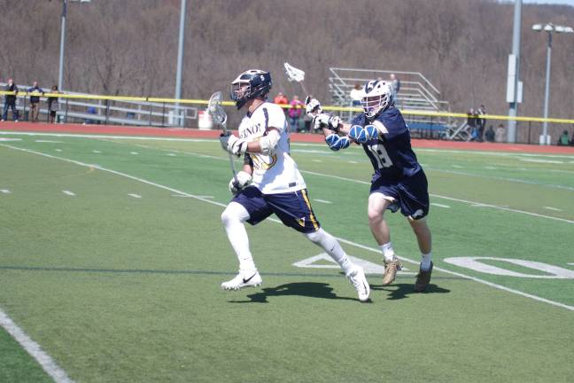 Vernon's Zack Biango carries the ball as Pope John's Keith Johnson closes in from behind. Biango scored one goal and scooped up six ground balls.