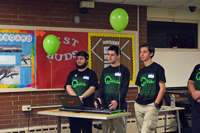 Josh Virtell (left) and Brian Hoskins (right) drive the robot and demonstrate its features, as Hunter Mitchell (far right) keeps a close eye out for any sudden distractions around the area