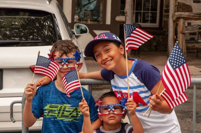 From left, Max Boslet, 6; Tristan Lorenzo, 4; and Sprena Lorenzo, 10; all from Sparta, waving the flag
