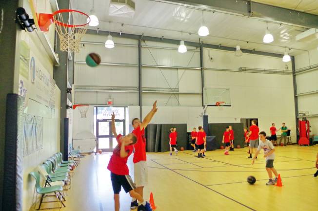 On Wednesday, July 19, BT Basketball staff member Ben Melville holds his hands up in a defensive posture as a camper takes a shot during a drill.
