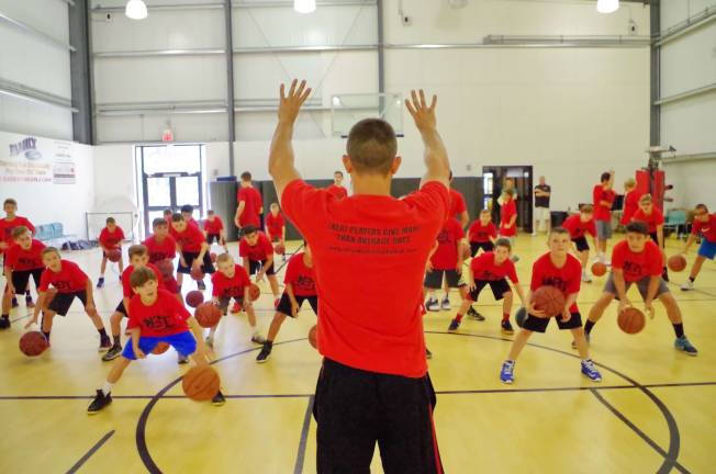 On Wednesday, July 19, BT Basketball founder Brian Thomas raises his arms as he instructs basketball campers.