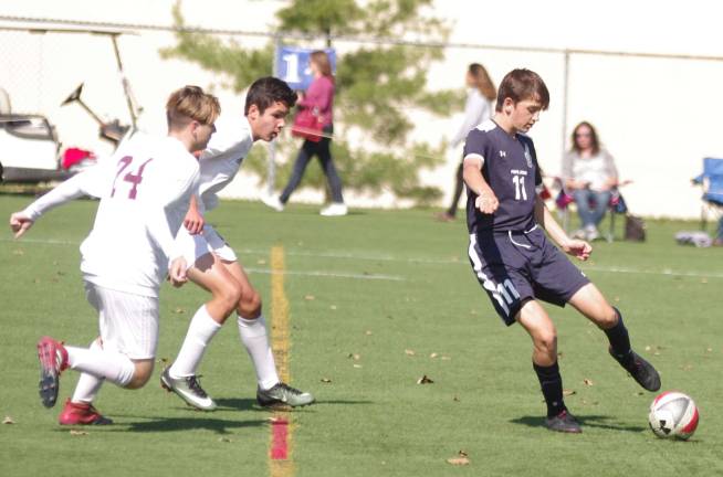 Pope John Lion Michael Skounakis is about to kick the ball as a pair of Newton Braves approach.