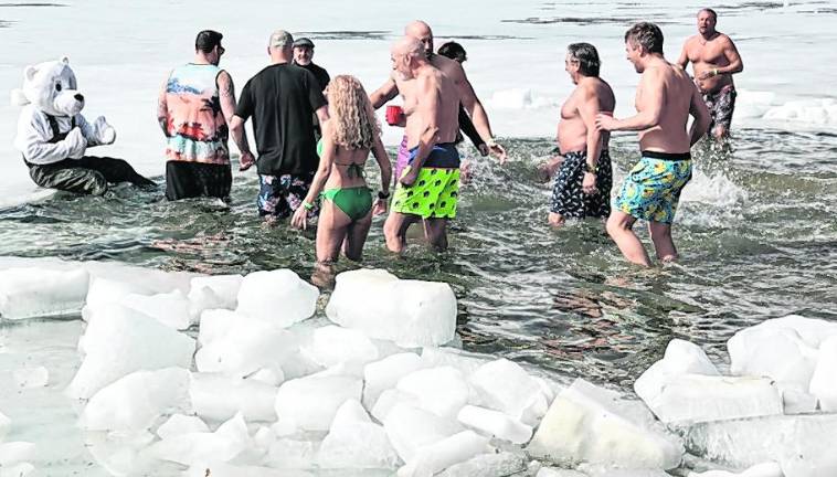 People wade into the water.