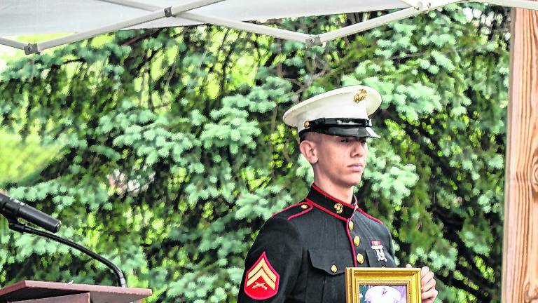 A marine holds a photo during the ceremony.