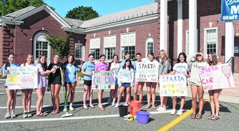 Members of the Sparta girls' tennis team promote their car wash with signs.